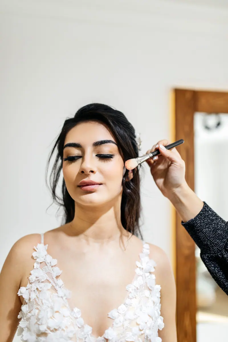 Bride gets final makeup touches before her wedding ceremony in elegant setting.
