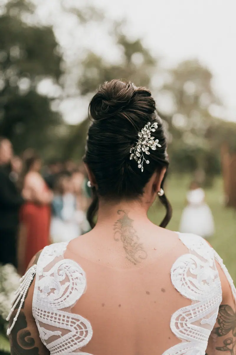 Bride with an elegant updo hairstyle adorned with jewel hairpiece outdoors at a wedding.