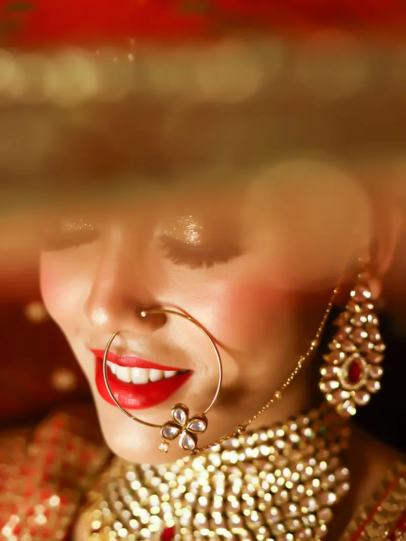 Close-up of an Indian bride smiling, adorned with intricate jewelry and traditional attire.