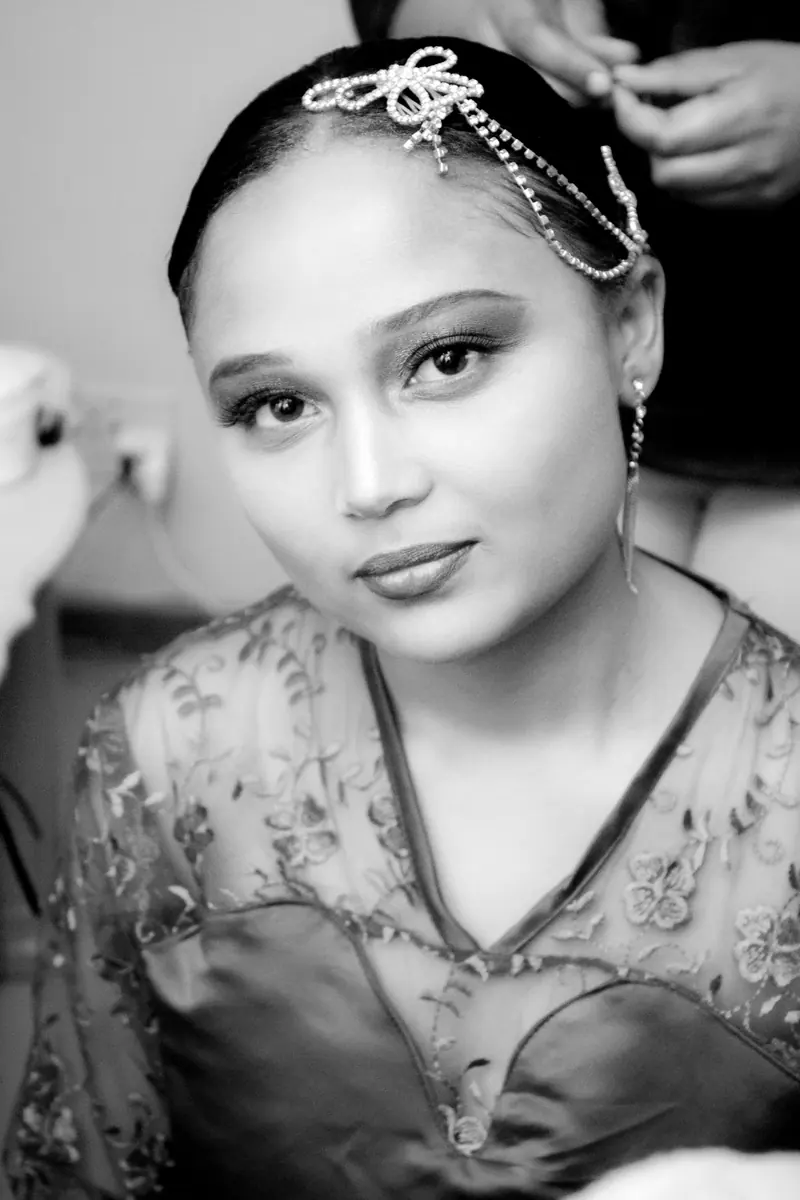 Black and white portrait of a bride in elegant attire, accented with jewelry and a detailed headpiece.