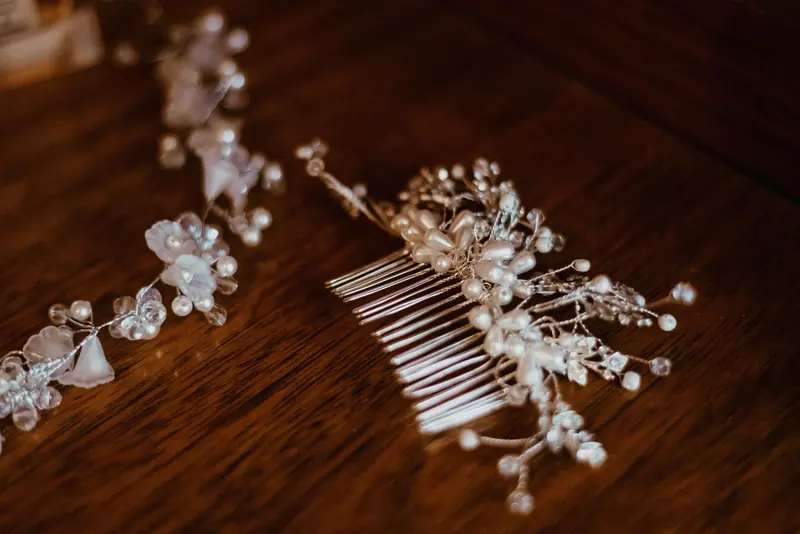Close-up of a delicate pearl and crystal bridal hair comb resting on a wooden table.