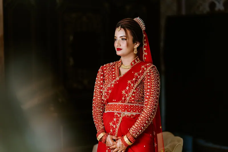 Elegant portrait of an Asian bride in a traditional red dress with intricate embroidery.