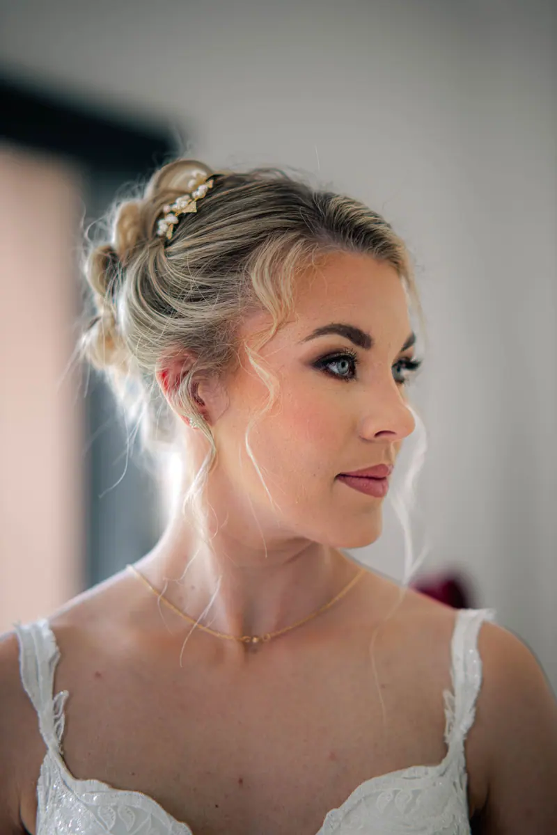 Beautiful blonde bride in white dress with elegant updo gazing sideways.