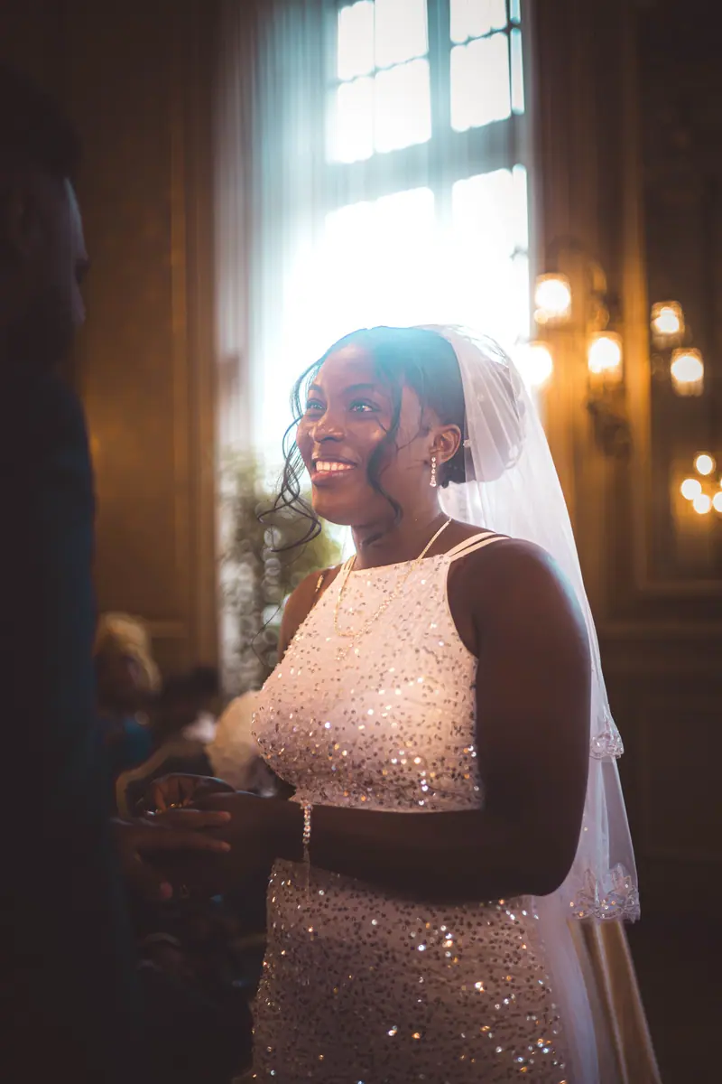 Radiant bride in white gown at luxurious indoor wedding, bathed in warm light.