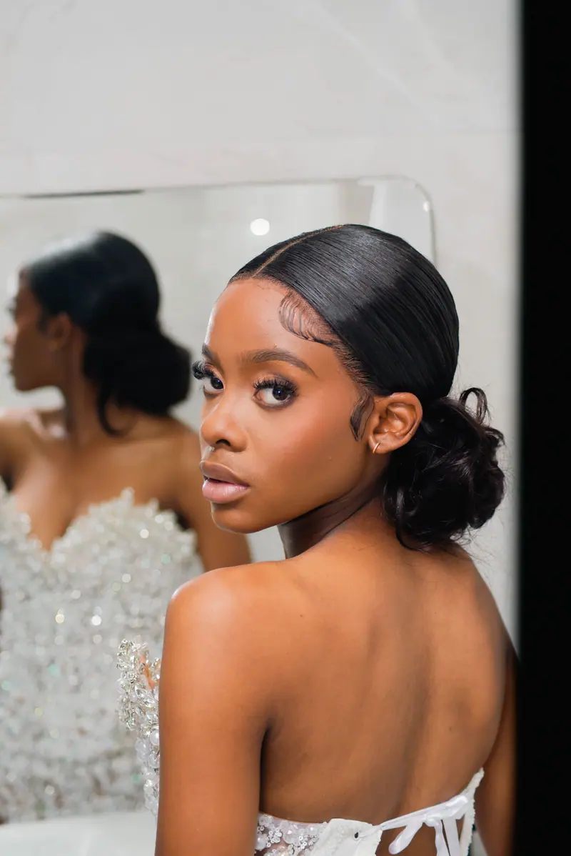 Glamorous young woman in evening wear gazing into a mirror, reflecting elegance.