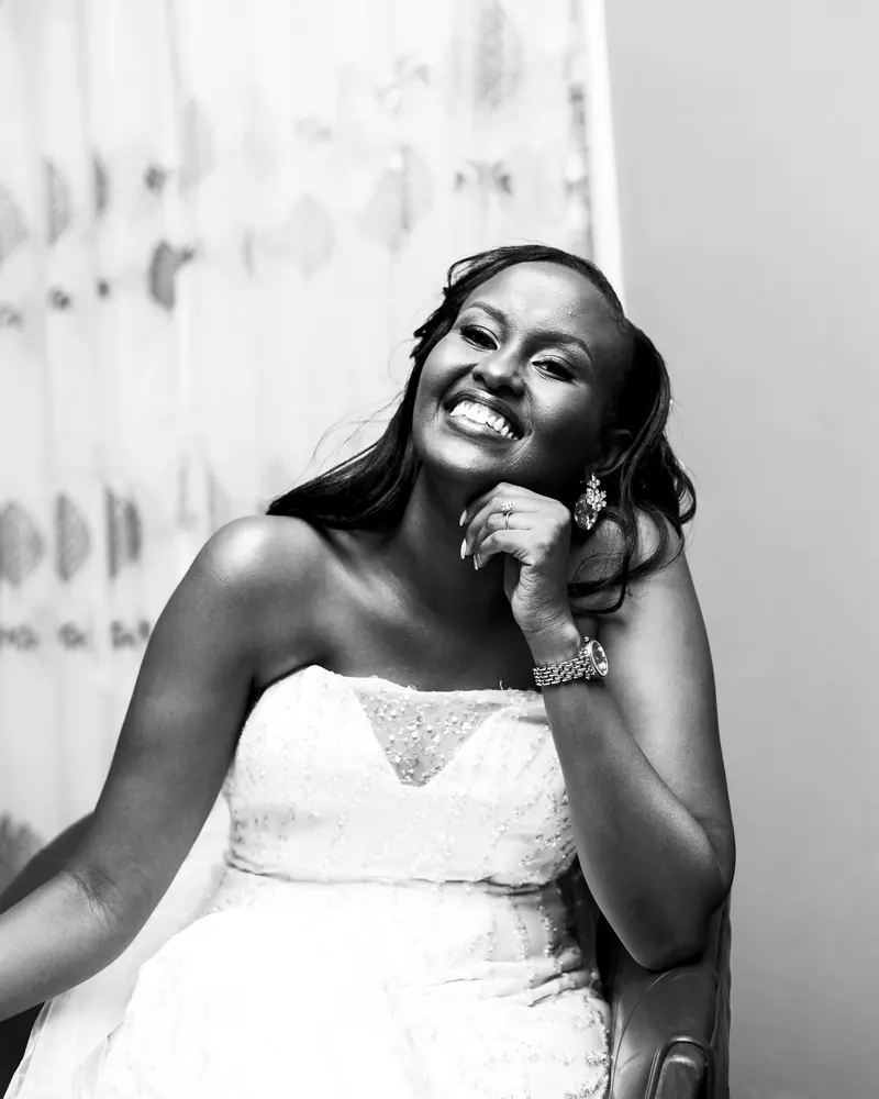 Elegant black and white portrait of a smiling bride in a strapless gown indoors.