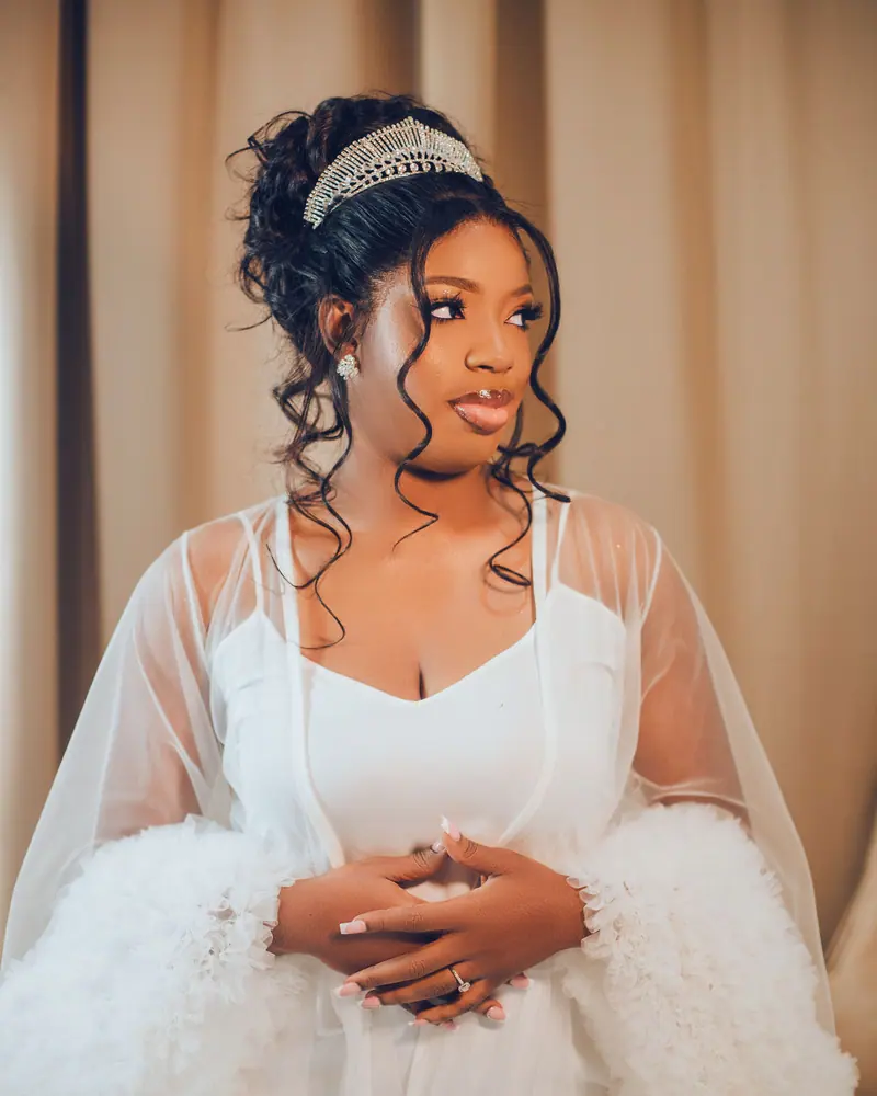 A beautiful bride in a white gown and tiara, standing gracefully in Abuja, Nigeria.