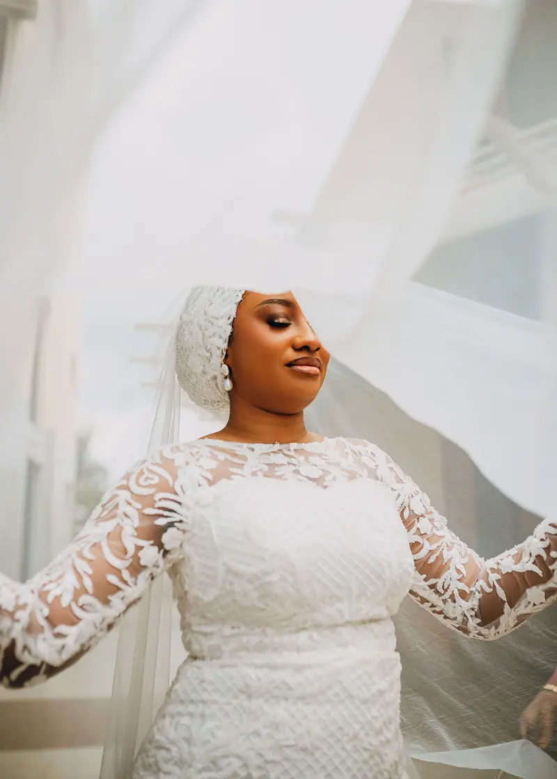 Beautiful bride in detailed lace dress enjoys a serene moment on her wedding day.