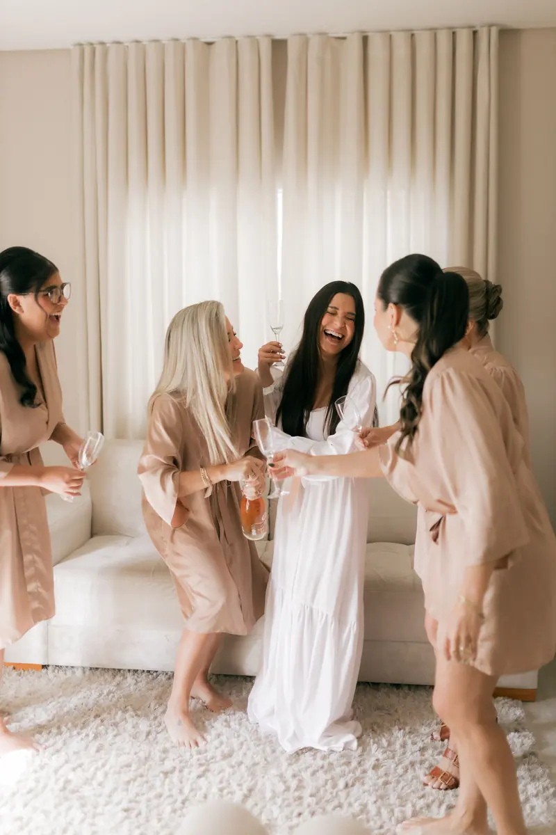 Joyful bridal party in robes toasting champagne indoors. Perfect for wedding themes.