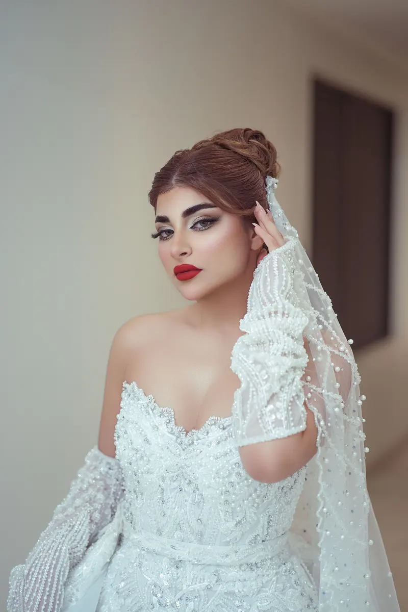 Portrait of a beautiful bride in a detailed pearl gown indoors, exuding elegance and sophistication.
