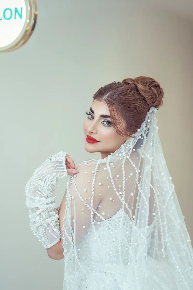 Beautiful bride in a pearl-embellished gown with a chic updo, captured indoors with a vintage feel.