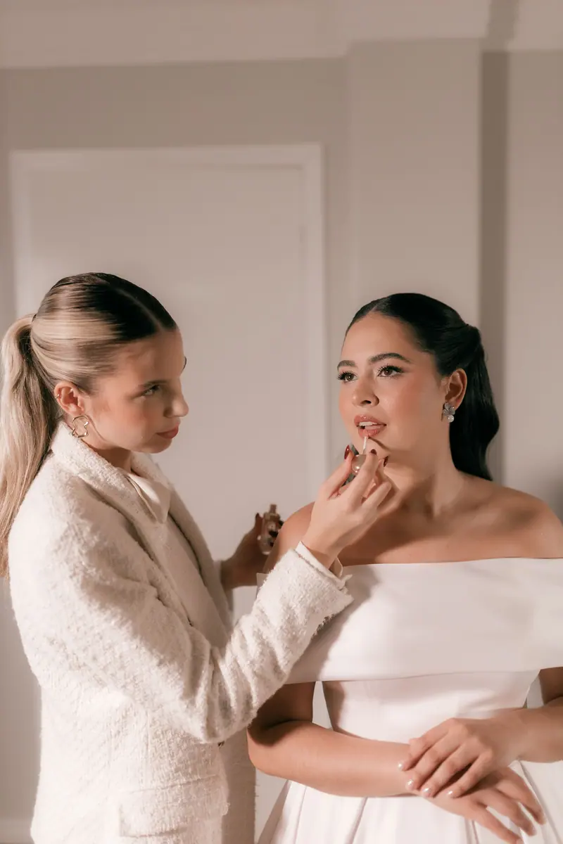 Bride receiving professional makeup application in a stylish indoor setting.