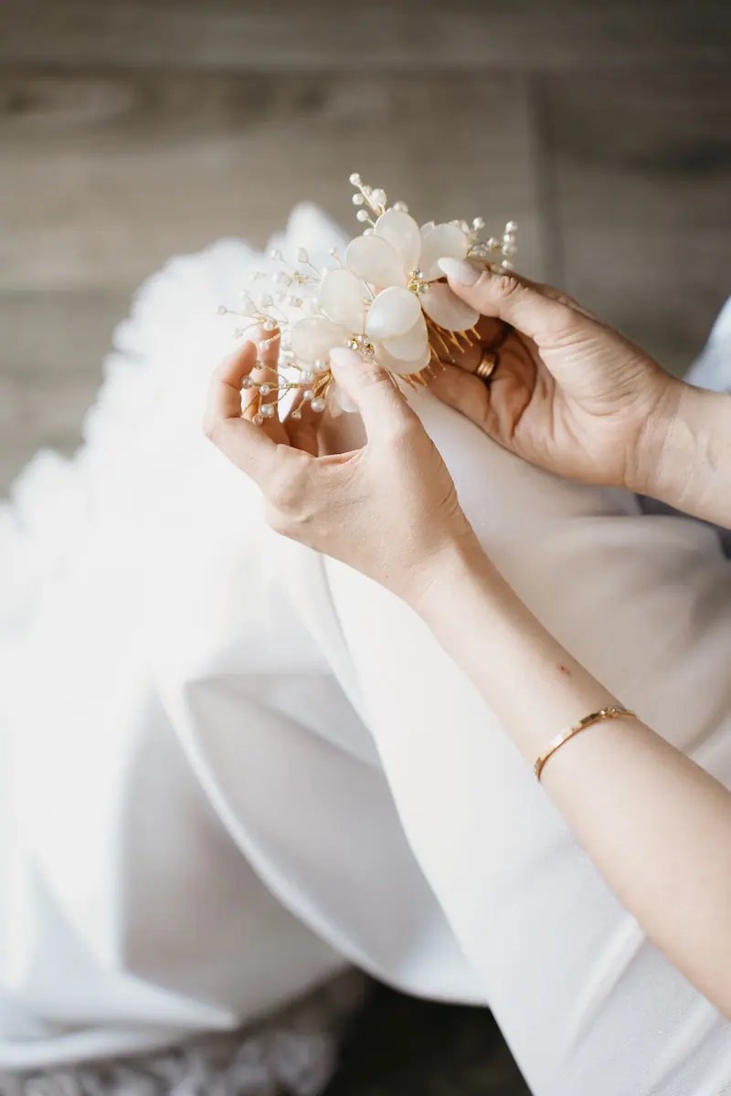 Close-up of a bride holding a delicate hair accessory with pearls and flowers.
