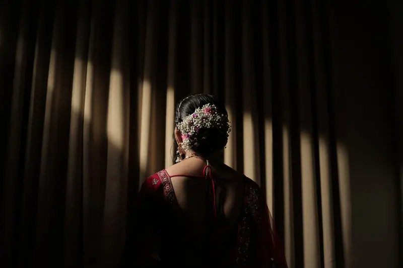 A bride in a traditional red dress, elegantly posed with floral hair accessories.