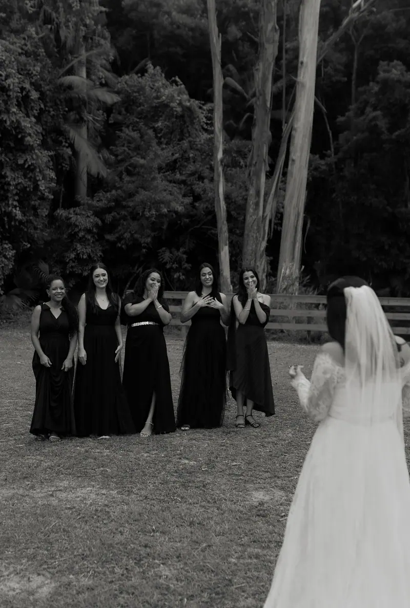 Bride joyfully tossing bouquet to excited bridesmaids in a scenic outdoor setting.