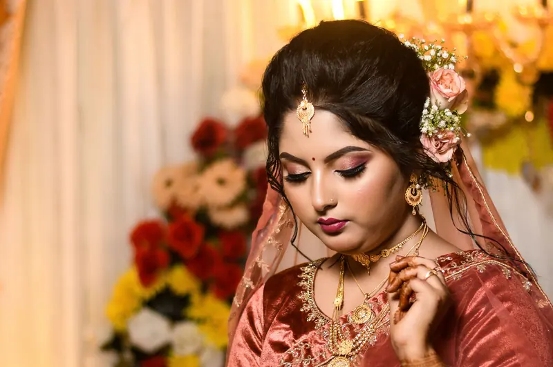 Beautiful bride adorned with traditional jewelry and floral accessory, showcasing cultural elegance.