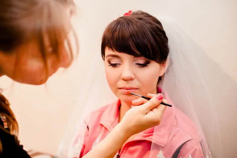 A bride getting her makeup done before the wedding ceremony.