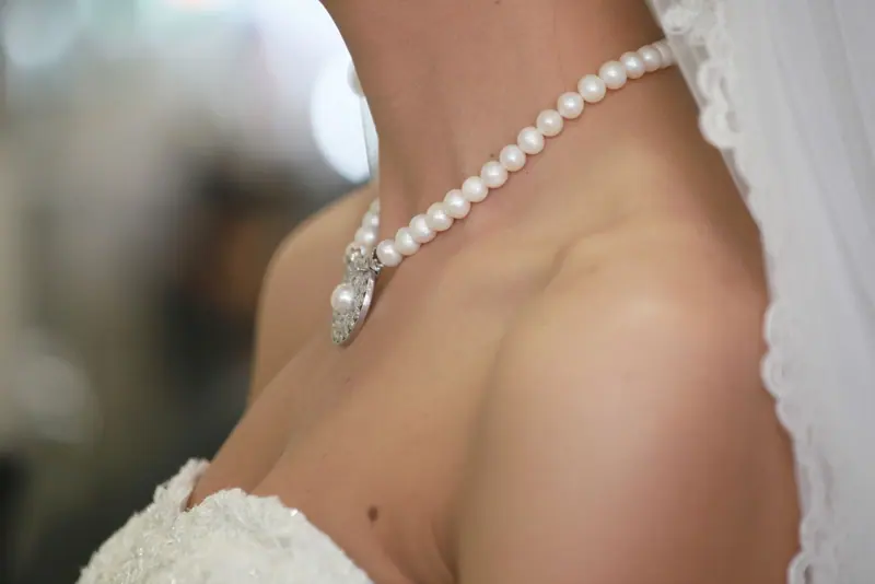 Closeup of a bride wearing an elegant pearl necklace, emphasizing timeless beauty and elegance.