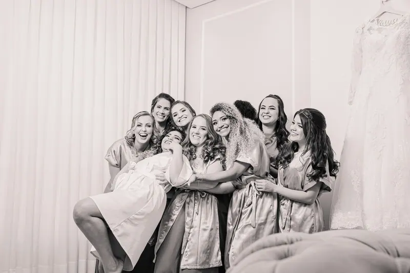 Happy bridesmaids in robes joyfully gathered together indoors, celebrating before the wedding.