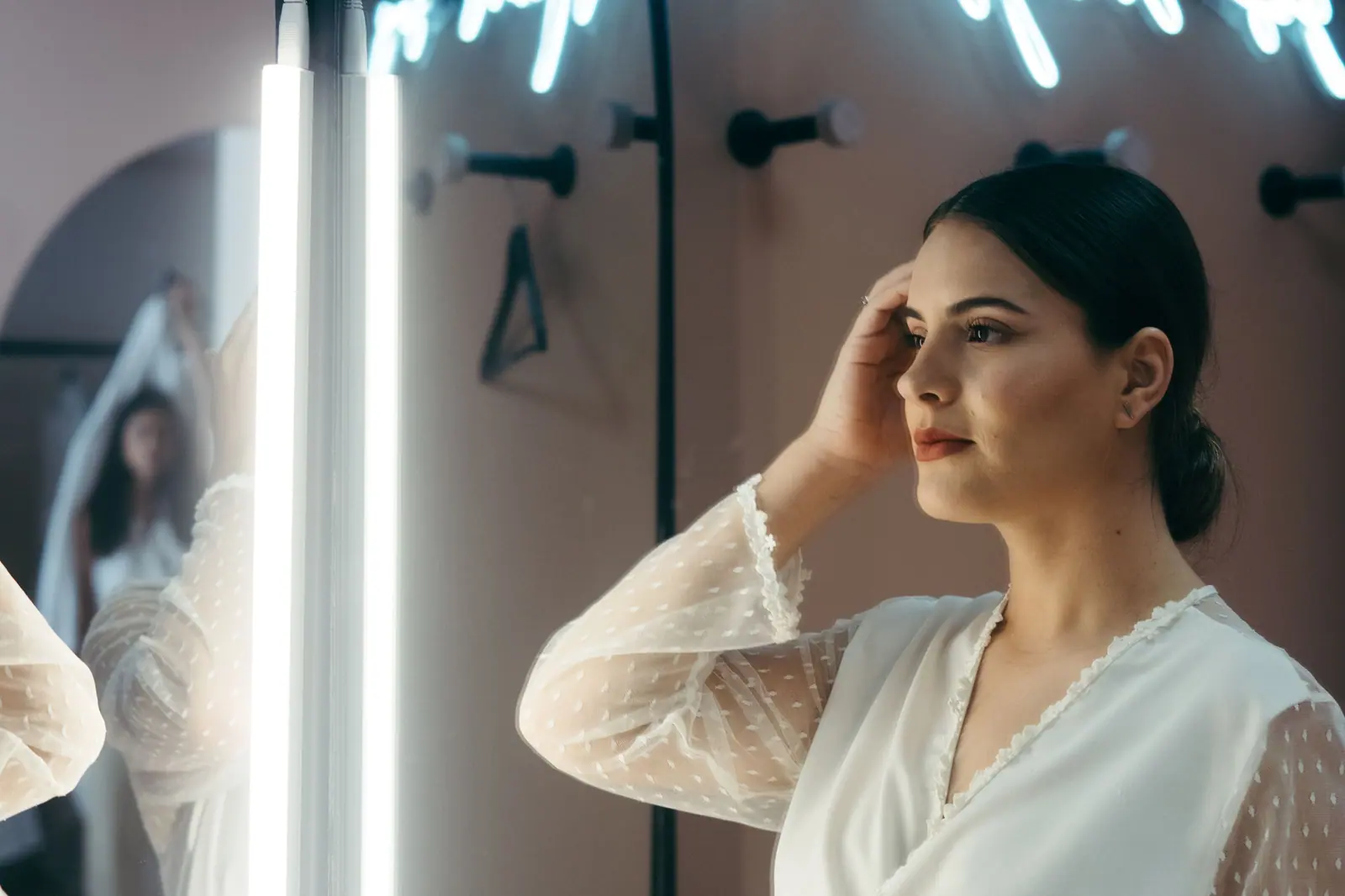 A bride admires herself in the mirror, prepping for her wedding day with elegance and poise.