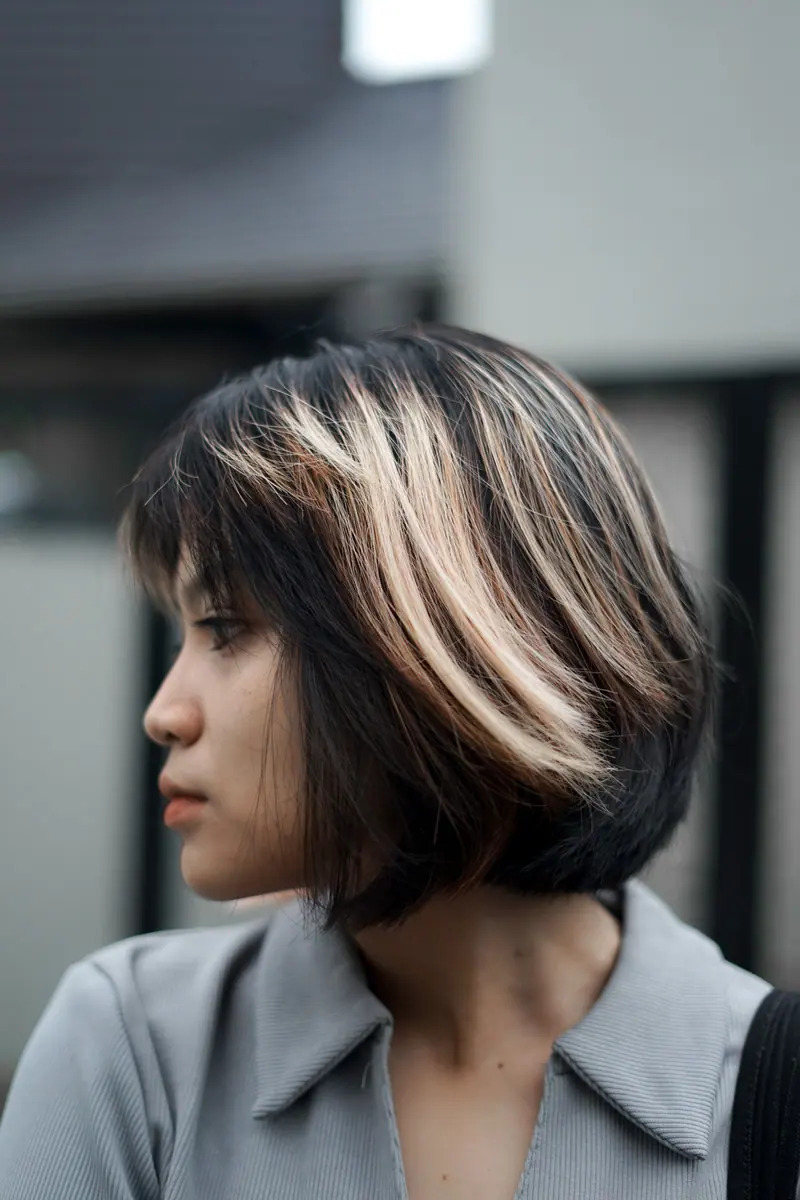 Profile portrait of a woman featuring trendy short hair with highlights.