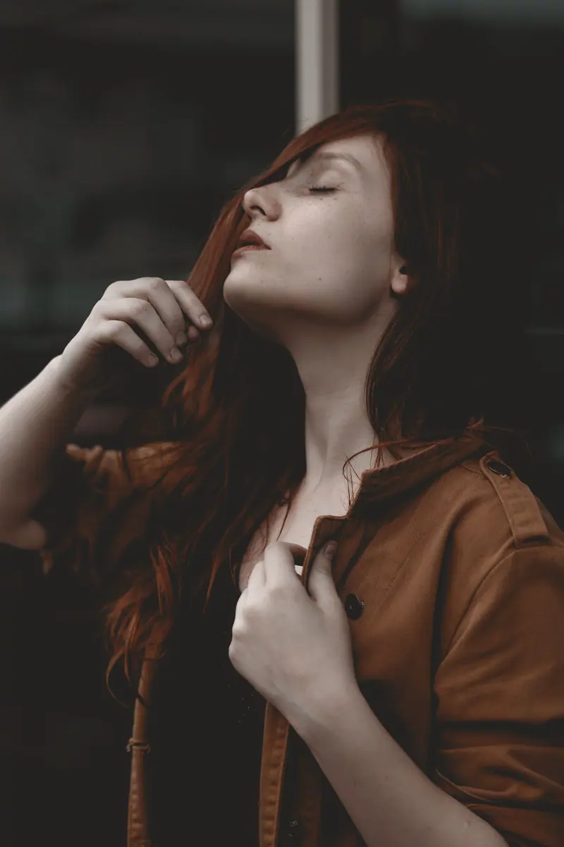 Elegant portrait of a woman with auburn hair in a contemplative pose, eyes gently closed.