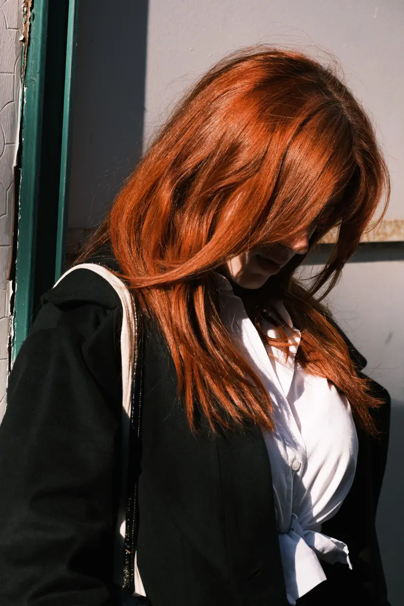 Fashionable redhead woman in a stylish outfit captured under natural light.