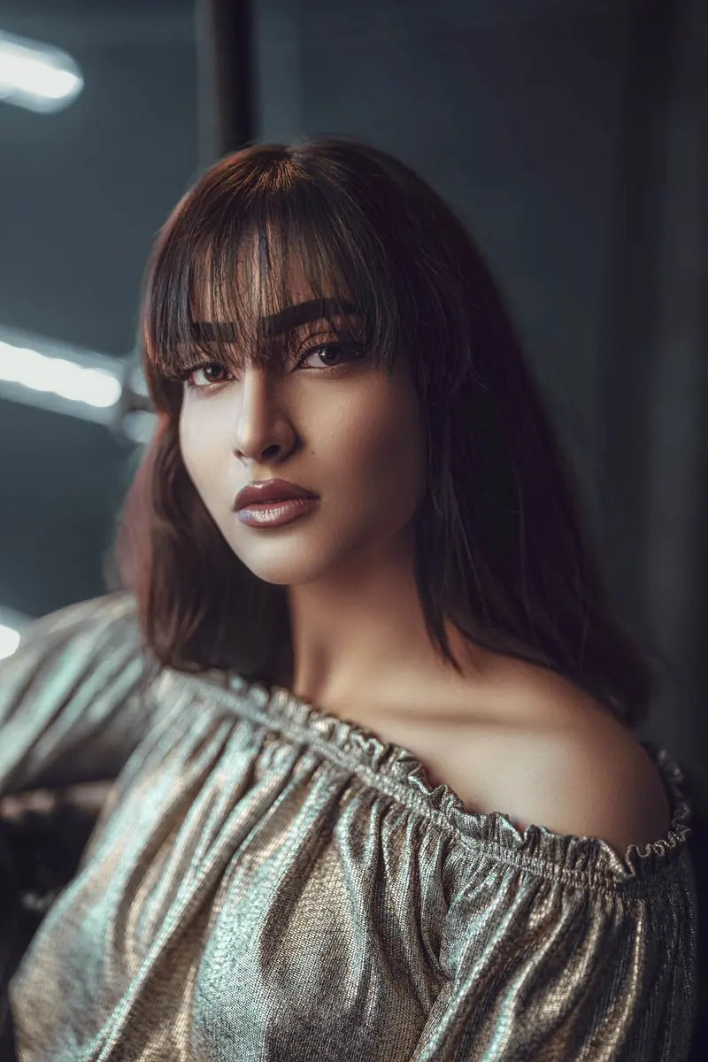 Sophisticated portrait of a young brunette woman in an off-shoulder blouse, exuding elegance and glamour.