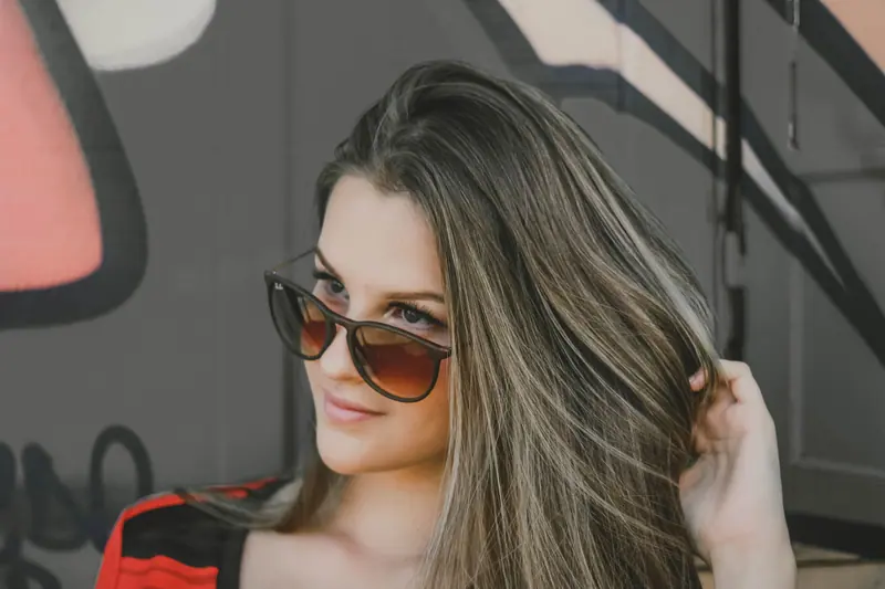 Portrait of a fashionable woman in sunglasses against a graffiti wall, exuding urban style.