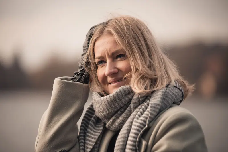 Smiling woman in cozy autumn attire near a lake in Weßling.