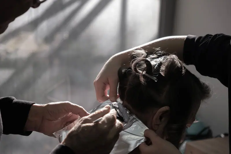 Expert hairdresser applying color highlights in a salon with natural lighting in İzmir, Türkiye.