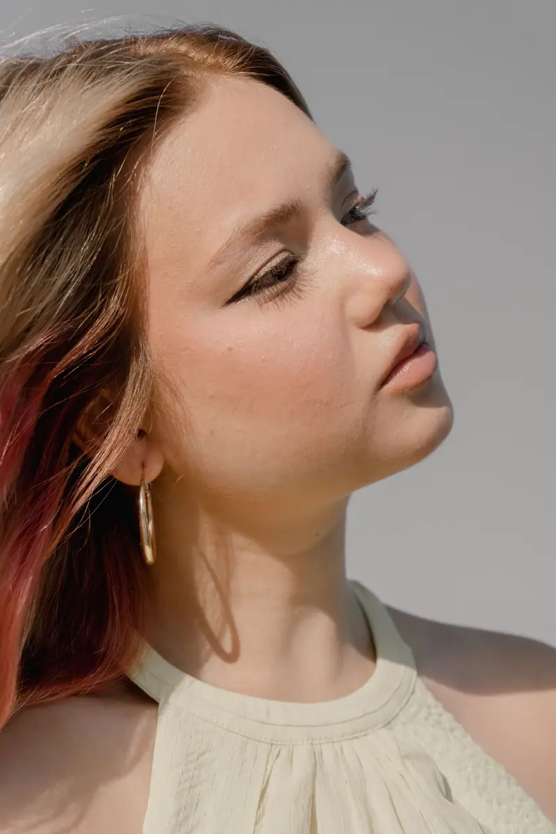Close-up portrait of a young woman with sunlight and wind in her hair outdoors.