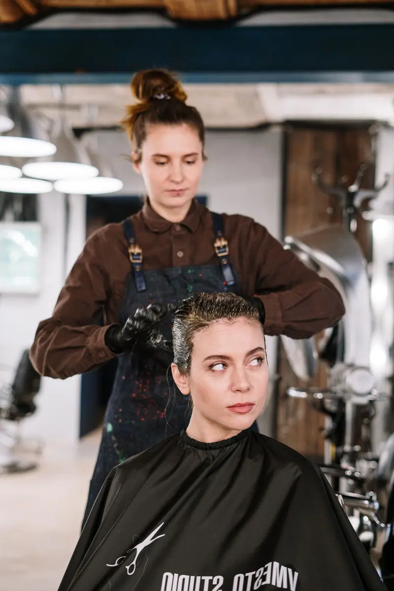 Hairdresser styling a woman's hair in a modern salon setting.