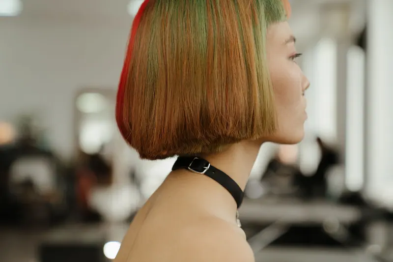 Profile shot of a woman with vibrant, multi-colored bob hairstyle in a modern studio.