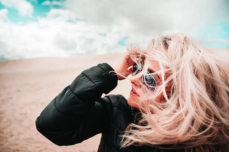 Woman with pastel pink hair blowing in the desert wind