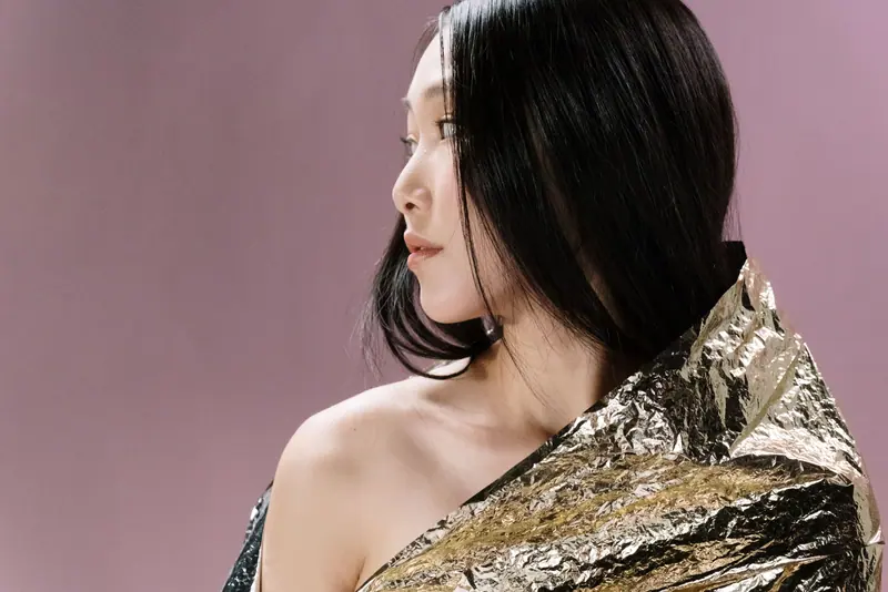 Elegant portrait of a woman wrapped in metallic foil against a purple backdrop.