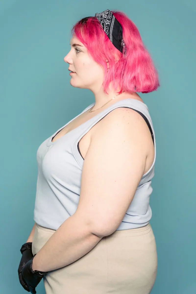 Side view of a woman with vibrant pink hair on blue background.