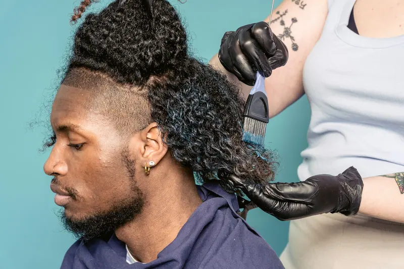 Colorist brushing vivid dye through a client's curls