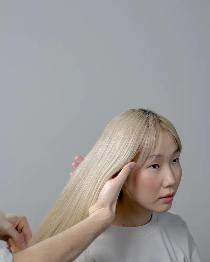 Blonde Asian woman having her hair styled at a salon by a professional hairdresser
