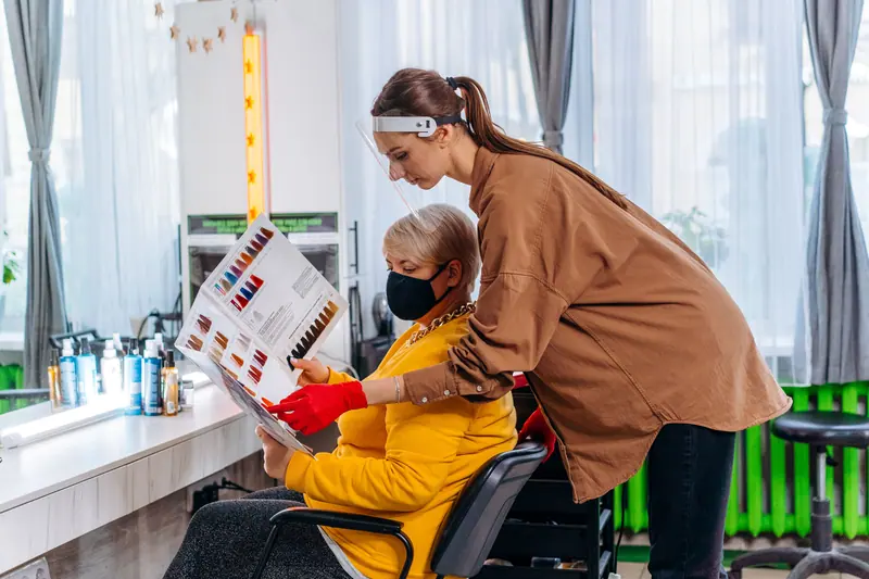 Hair stylist helping client choose hair color in a modern salon setting.
