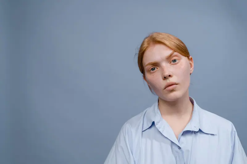 Woman with soft strawberry-blonde hair against a grey-blue backdrop