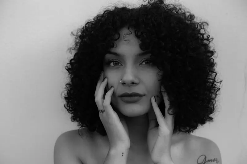 Elegant black and white portrait of a woman with curly hair and expressive pose.