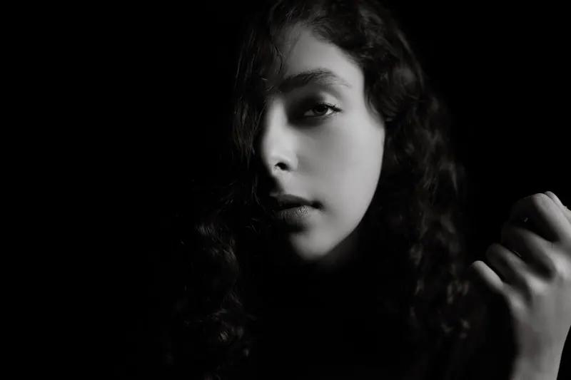 Dramatic black and white portrait of a woman with curly hair, capturing emotions.