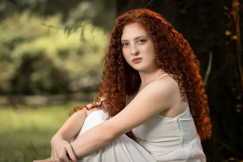 Portrait of a red-haired woman sitting outdoors with lush green background in Costa Rica.