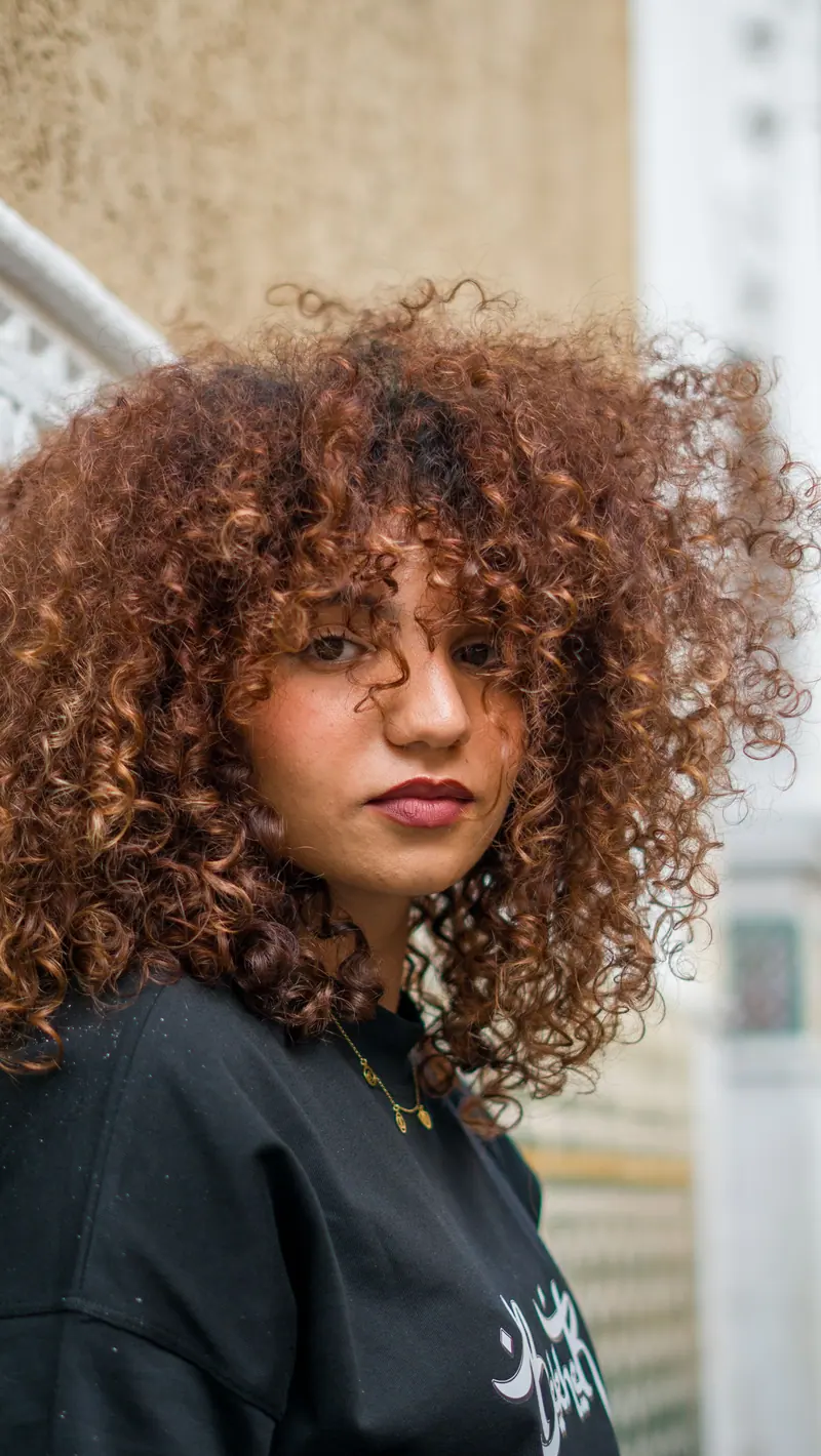 Portrait of a fashionable woman with curly hair in an urban environment. Perfect for lifestyle themes.