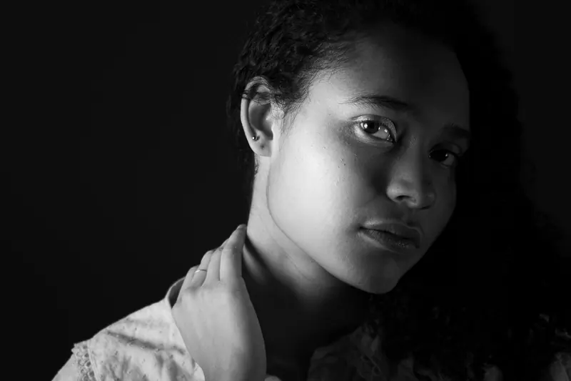 Striking black and white portrait of a woman with curly hair in a studio setting.
