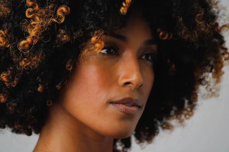 A striking close-up portrait of a woman with beautiful curly hair against a soft background.