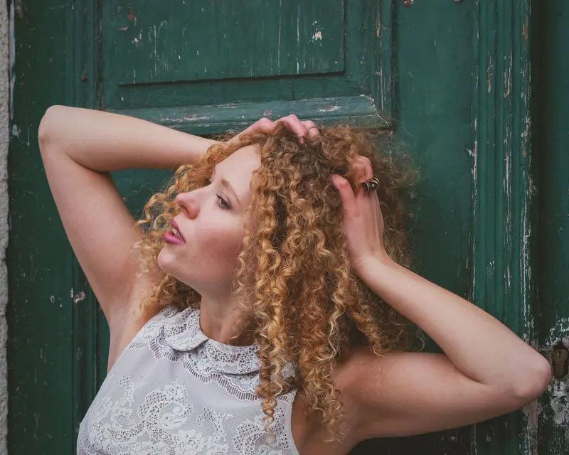 Captivating outdoor portrait of a woman with curly hair against a rustic green door backdrop.