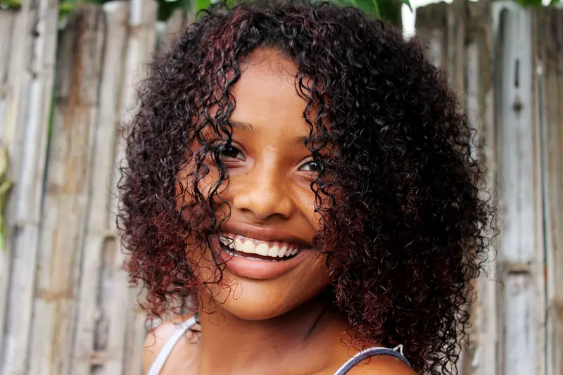 Bright portrait of a woman with curly afro hair, smiling outdoors in Colombia.