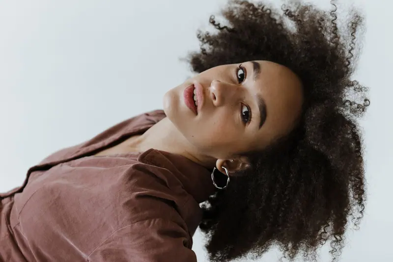 Studio portrait of a young woman with afro hair showcasing natural beauty and fashion style.